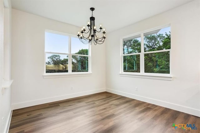 unfurnished dining area featuring hardwood / wood-style flooring and an inviting chandelier