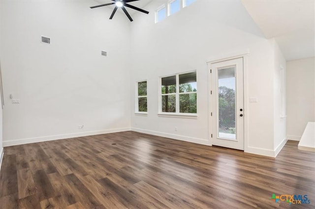 unfurnished living room featuring ceiling fan, dark hardwood / wood-style flooring, and a towering ceiling