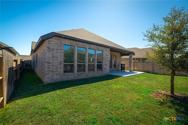 back of property with a patio, brick siding, a fenced backyard, and a lawn