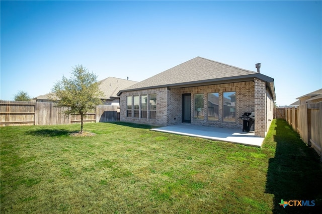 back of property with a lawn, a fenced backyard, a shingled roof, brick siding, and a patio area