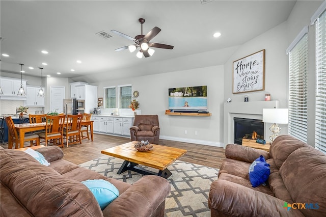 living area with light wood finished floors, visible vents, recessed lighting, and ceiling fan