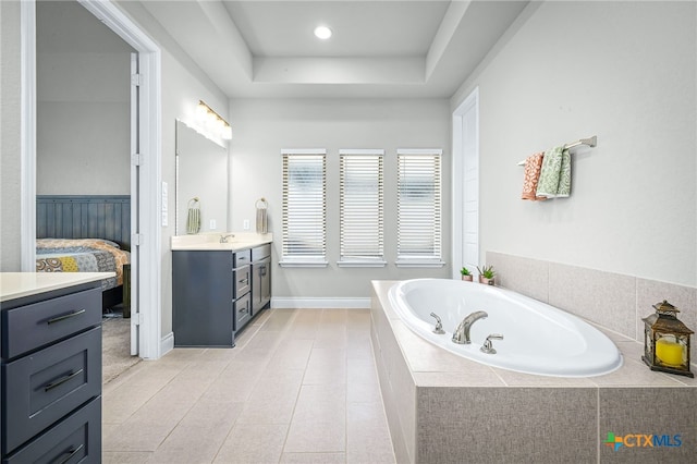 full bath featuring vanity, ensuite bath, a tray ceiling, recessed lighting, and a bath