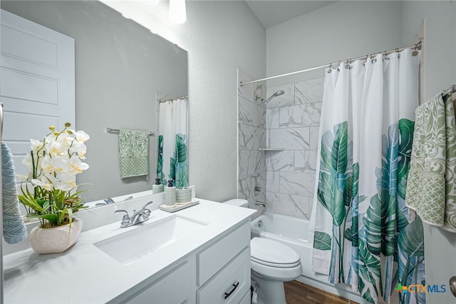 full bathroom with vanity, wood finished floors, shower / bath combination with curtain, toilet, and a textured wall