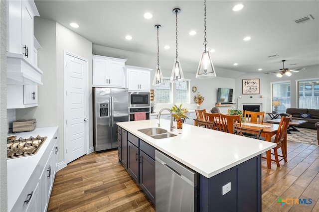 kitchen featuring visible vents, a ceiling fan, a sink, dark wood finished floors, and stainless steel appliances