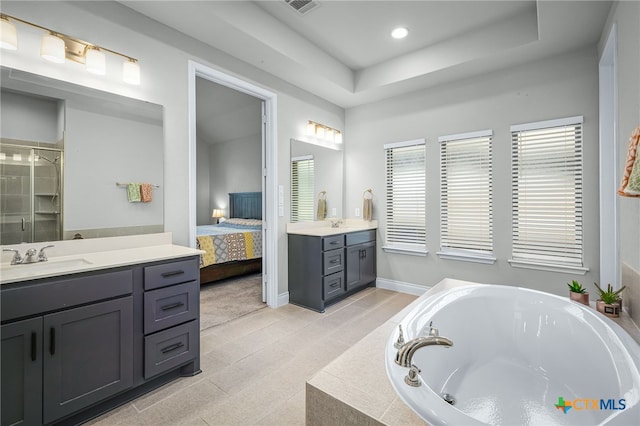 ensuite bathroom featuring a garden tub, two vanities, ensuite bathroom, a raised ceiling, and a sink