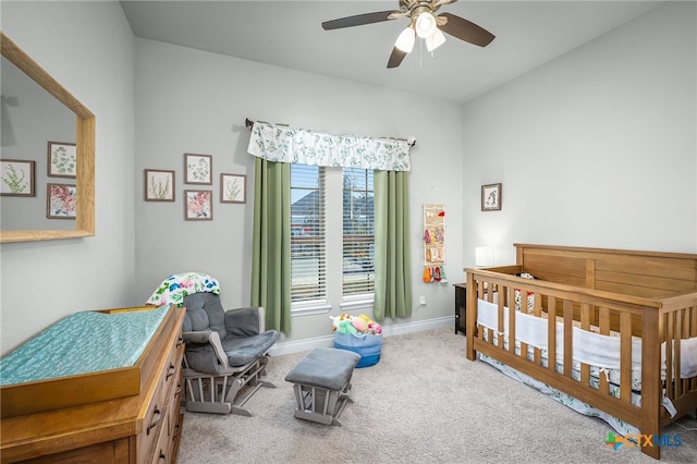 carpeted bedroom featuring a crib, baseboards, and ceiling fan