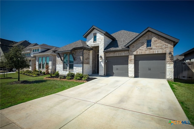 french provincial home with brick siding, an attached garage, a front yard, stone siding, and driveway