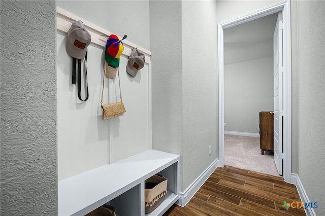 mudroom featuring baseboards, dark wood finished floors, and a textured wall