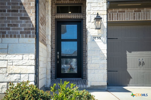 property entrance featuring brick siding, a garage, and stone siding