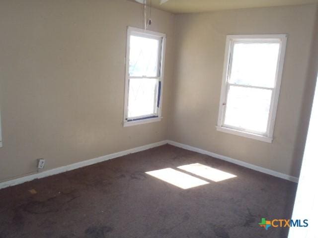 spare room featuring carpet and baseboards