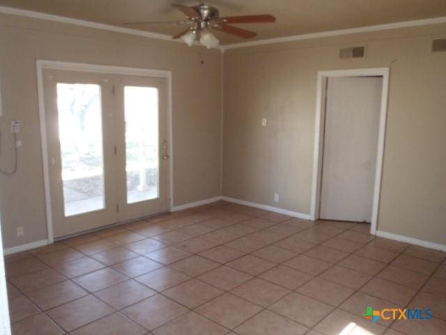 spare room with ornamental molding, plenty of natural light, and light tile patterned flooring