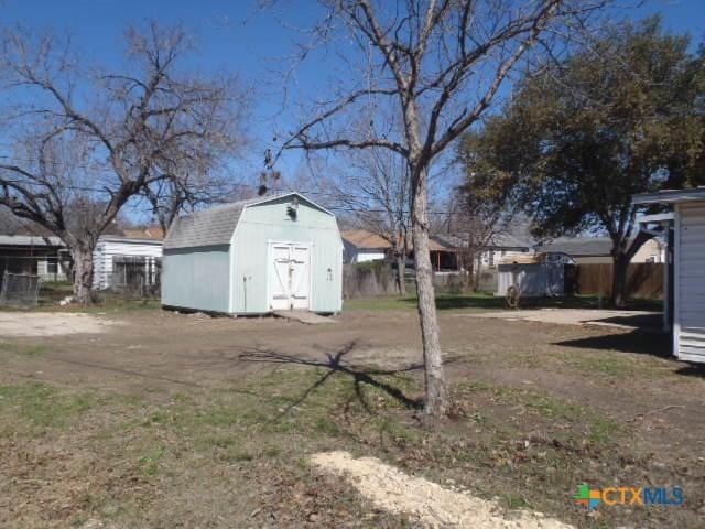 view of yard featuring a storage shed, an outdoor structure, and fence