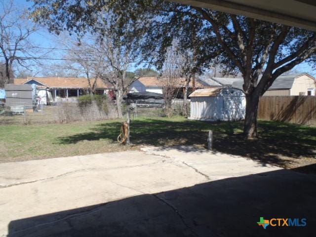 view of patio with an outbuilding, a storage shed, and fence