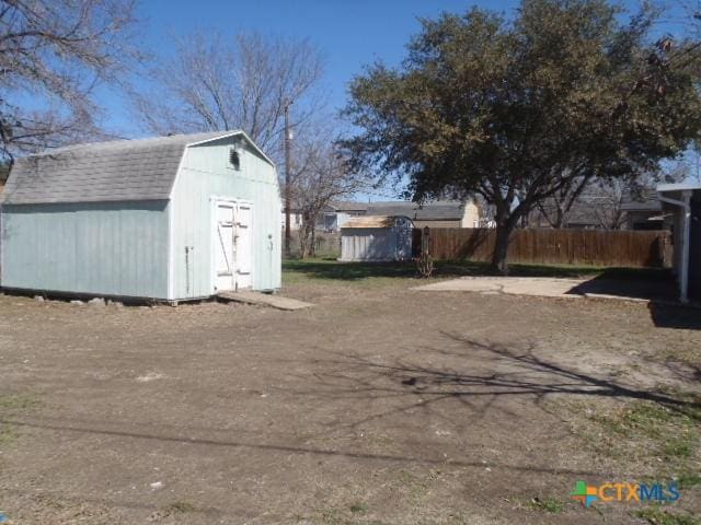 exterior space featuring a storage shed, fence, and an outdoor structure