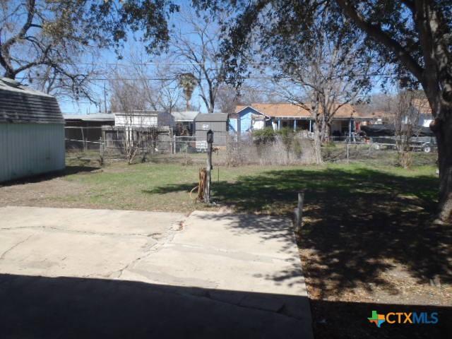 view of yard featuring a storage shed, an outdoor structure, and fence