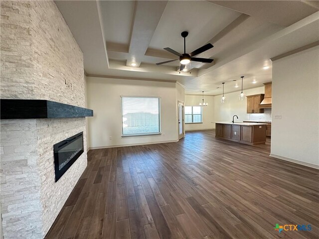 unfurnished living room featuring coffered ceiling, ceiling fan, beam ceiling, hardwood / wood-style floors, and a stone fireplace