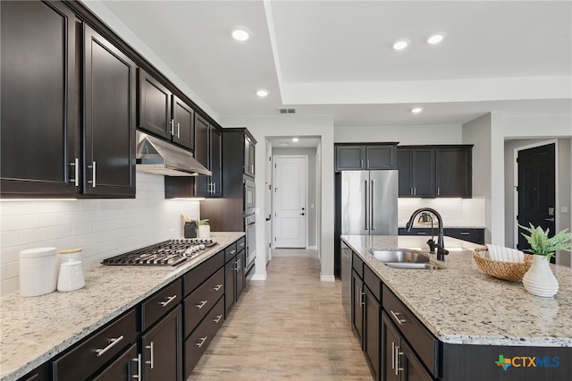 117 Ace Ln Unit 101, San Marcos, TX 78666 - kitchen featuring appliances with stainless steel finishes, under cabinet range hood, a center island with sink, light stone countertops, and backsplash