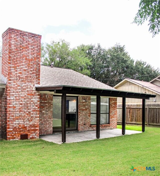 211 Alamogordo Dr, Victoria, TX 77904 - back of house featuring a shingled roof, a patio area, a chimney, and brick siding