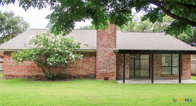 211 Alamogordo Dr, Victoria, TX 77904 - rear view of house with brick siding, roof with shingles, a patio area, a chimney, and a yard