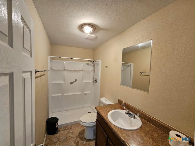 bathroom featuring a shower, vanity, a textured ceiling, and toilet