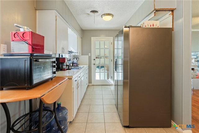806 S 23rd St, Copperas Cove, TX 76522 - kitchen featuring freestanding refrigerator, a sink, light countertops, white cabinets, and a textured ceiling