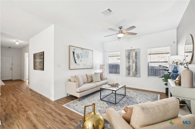 living room featuring wood-type flooring, ceiling fan, and a healthy amount of sunlight