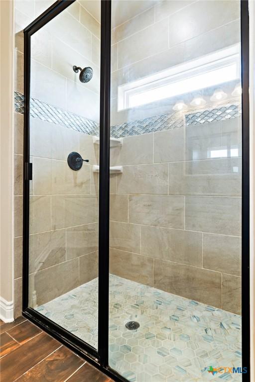 bathroom with wood-type flooring and a shower with shower door