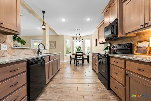 kitchen featuring plenty of natural light, sink, black appliances, and decorative light fixtures