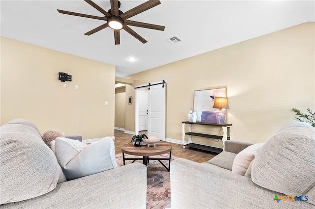 living room featuring hardwood / wood-style flooring, a barn door, and ceiling fan