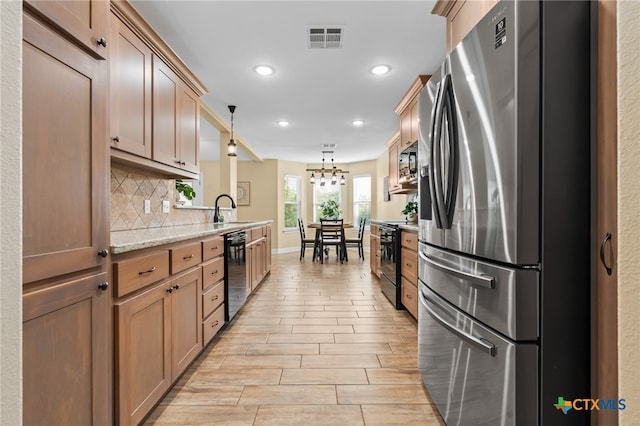 kitchen with sink, black appliances, backsplash, hanging light fixtures, and light wood-type flooring