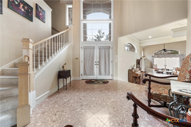 entrance foyer with french doors, crown molding, and a high ceiling