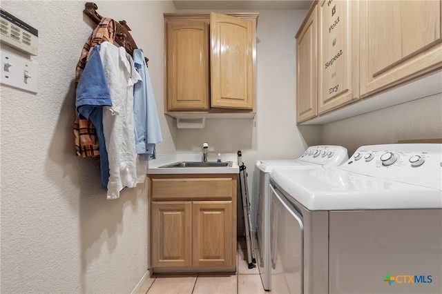 washroom with cabinets, washing machine and dryer, light tile patterned flooring, and sink