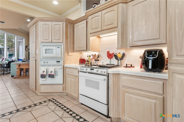 kitchen with tile countertops, white appliances, ornamental molding, light brown cabinetry, and light tile patterned flooring