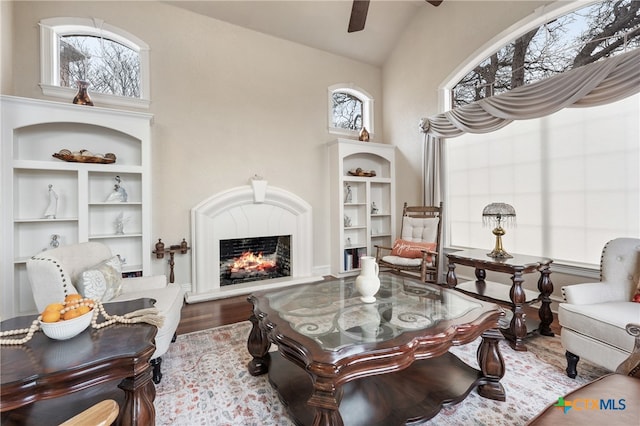 living room with built in shelves, wood-type flooring, and high vaulted ceiling