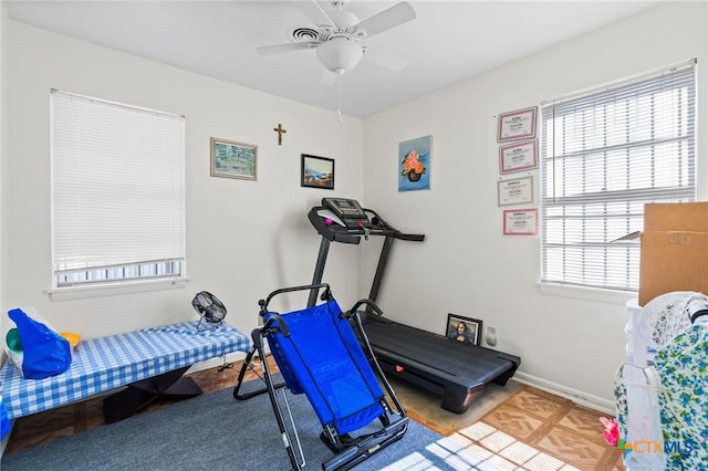 workout area featuring ceiling fan and baseboards