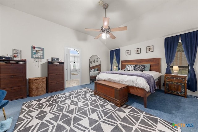 carpeted bedroom featuring ceiling fan, vaulted ceiling, and ensuite bath