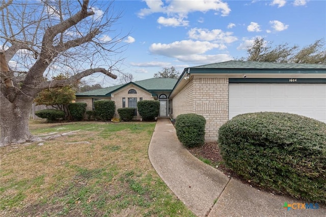 view of front of house with an attached garage, a front yard, and brick siding