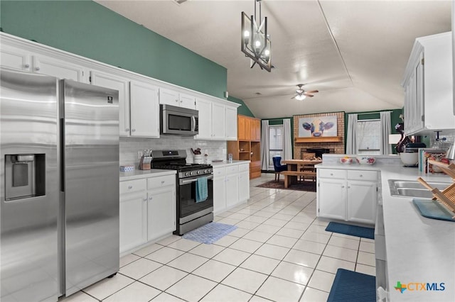 kitchen featuring light tile patterned floors, appliances with stainless steel finishes, white cabinetry, backsplash, and decorative light fixtures