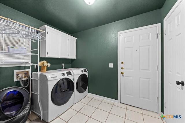 washroom featuring light tile patterned flooring, washing machine and clothes dryer, and cabinets