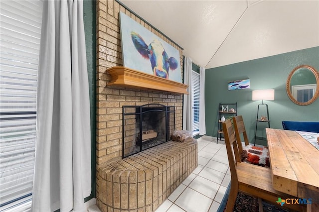 tiled living room with lofted ceiling and a brick fireplace