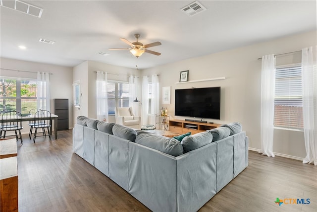living room featuring wood finished floors, a ceiling fan, and visible vents