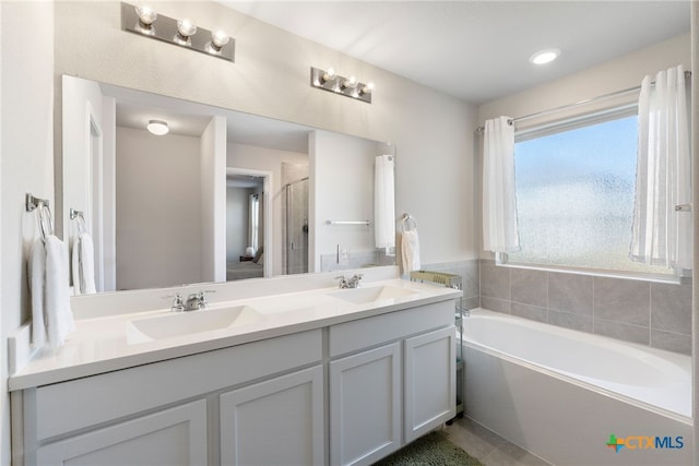full bathroom with a sink, double vanity, a stall shower, and a garden tub
