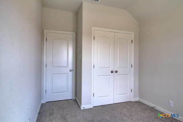 unfurnished bedroom with a closet, lofted ceiling, and carpet flooring