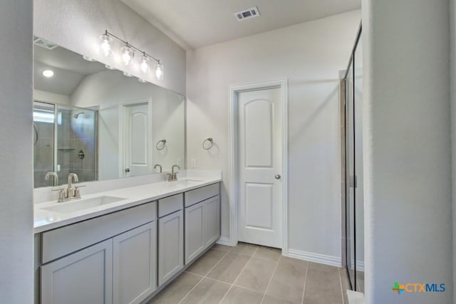 bathroom featuring a shower with shower door, vanity, and tile patterned floors