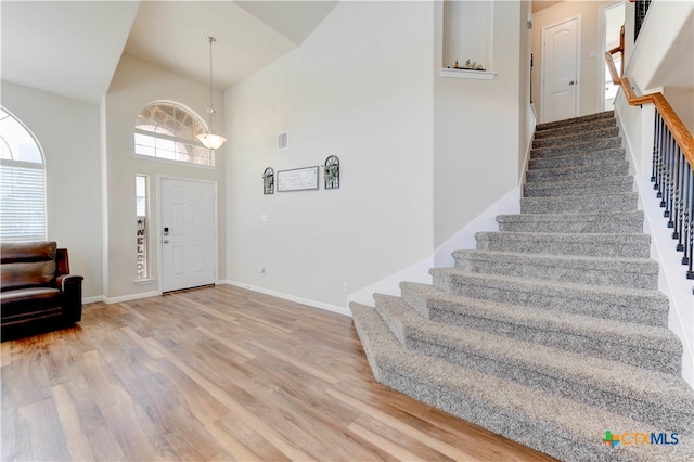 foyer entrance featuring high vaulted ceiling and wood-type flooring