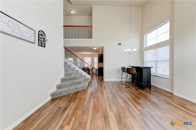 foyer entrance featuring hardwood / wood-style floors, a high ceiling, and a notable chandelier