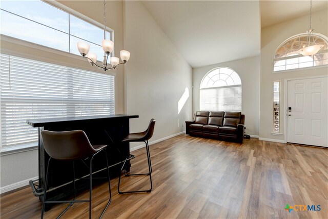 dining space featuring hardwood / wood-style flooring, high vaulted ceiling, and a notable chandelier