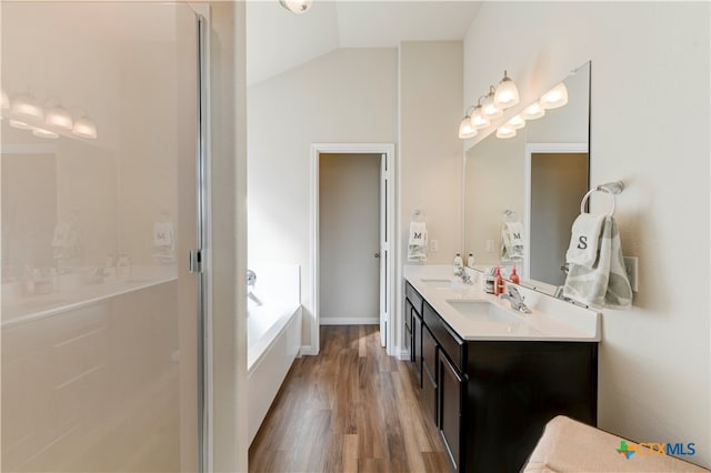 bathroom with vanity, hardwood / wood-style flooring, plus walk in shower, and vaulted ceiling