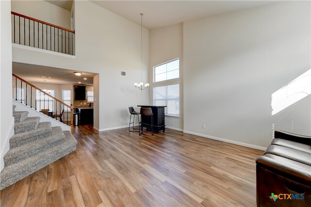 unfurnished living room with hardwood / wood-style floors, plenty of natural light, and a high ceiling