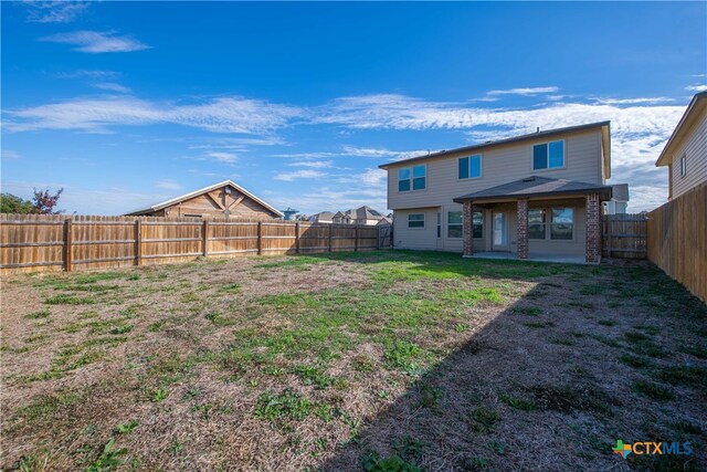 rear view of property featuring a lawn and a patio area